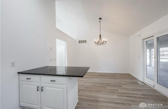 kitchen featuring visible vents, light wood-style flooring, dark countertops, white cabinetry, and lofted ceiling