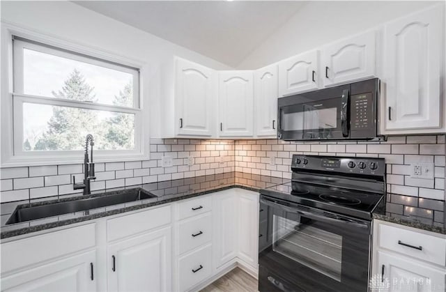 kitchen with dark stone countertops, a sink, black appliances, vaulted ceiling, and tasteful backsplash