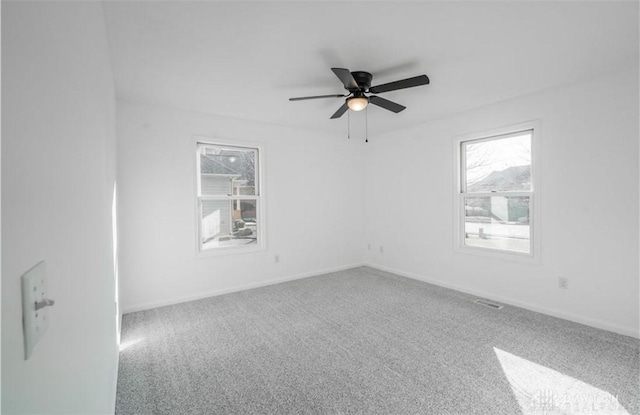 carpeted empty room with baseboards, plenty of natural light, and a ceiling fan