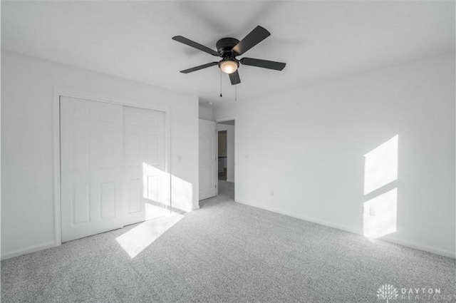 unfurnished bedroom featuring a closet, carpet flooring, baseboards, and a ceiling fan