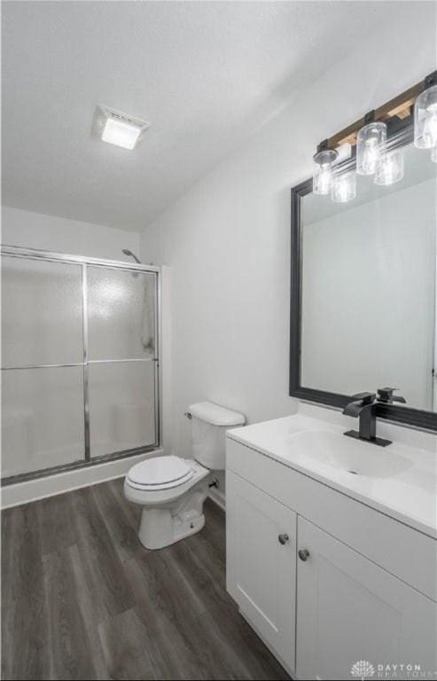 full bath featuring toilet, vanity, an enclosed shower, and wood finished floors