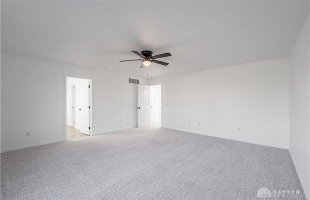 unfurnished room featuring baseboards, light colored carpet, visible vents, and ceiling fan