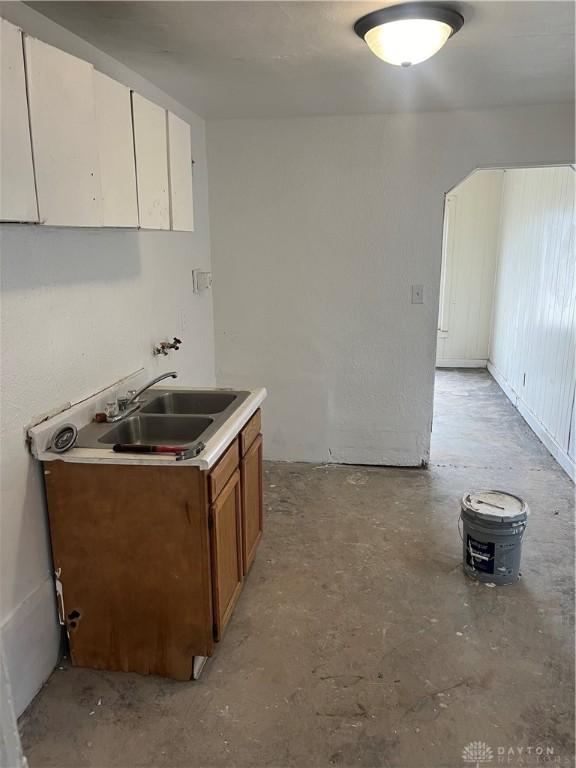 kitchen featuring concrete floors, a sink, white cabinetry, and brown cabinets