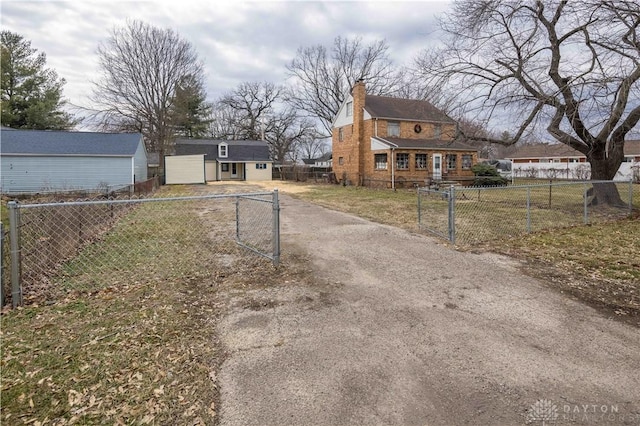 exterior space with a front yard, a fenced front yard, dirt driveway, and an outbuilding