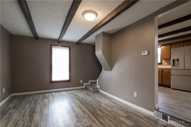 bonus room featuring stairway, a textured ceiling, wood finished floors, beamed ceiling, and baseboards