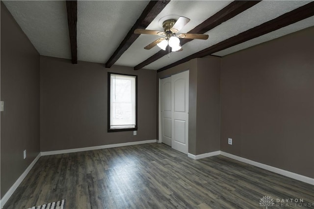 unfurnished bedroom featuring a textured ceiling, wood finished floors, beam ceiling, and baseboards