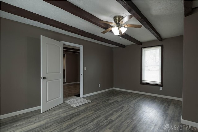 empty room with a textured ceiling, baseboards, beam ceiling, and wood finished floors