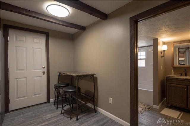 dining space featuring wood finished floors, beam ceiling, and baseboards