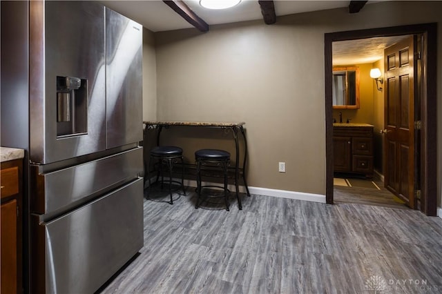 interior space featuring beam ceiling, baseboards, and wood finished floors