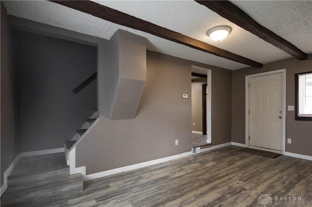 foyer entrance with baseboards, wood finished floors, stairs, a textured ceiling, and beam ceiling