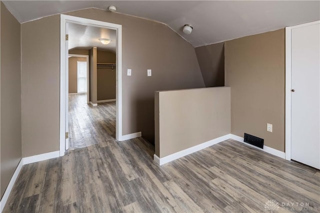 bonus room featuring visible vents, vaulted ceiling, baseboards, and wood finished floors