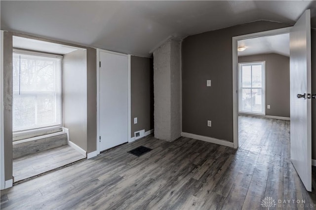 unfurnished room featuring lofted ceiling, wood finished floors, visible vents, and baseboards