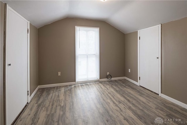 additional living space featuring lofted ceiling, a healthy amount of sunlight, baseboards, and wood finished floors