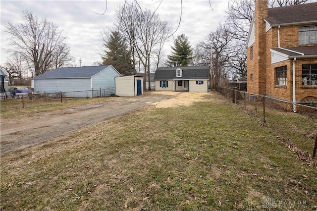 view of yard with an outbuilding, driveway, and a fenced backyard