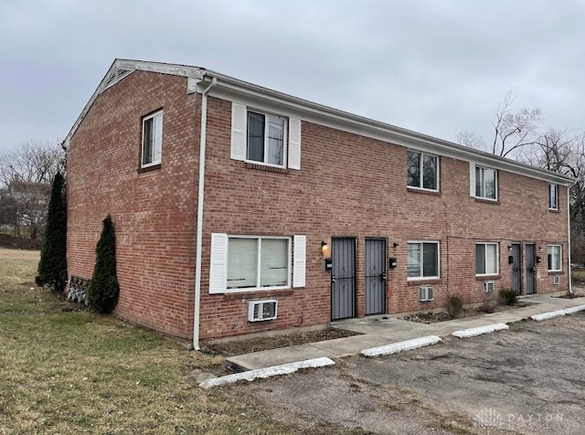 multi unit property featuring a front lawn and brick siding