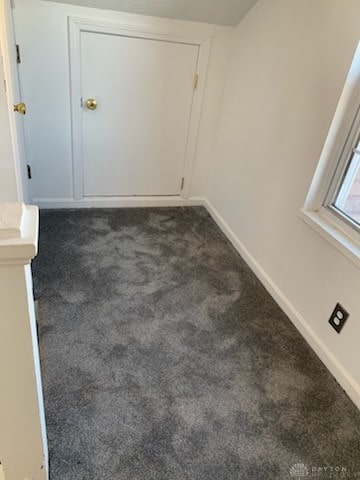 interior space with dark carpet and baseboards