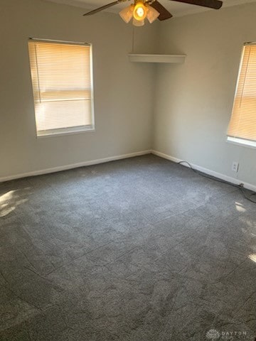 spare room with ceiling fan, baseboards, and dark colored carpet