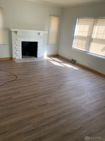 unfurnished living room featuring crown molding, visible vents, a fireplace, and wood finished floors