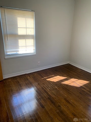 spare room featuring wood-type flooring and baseboards