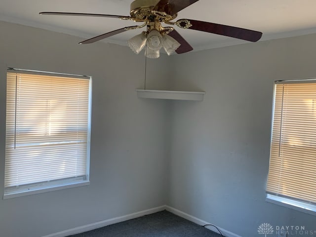 carpeted spare room featuring baseboards and crown molding