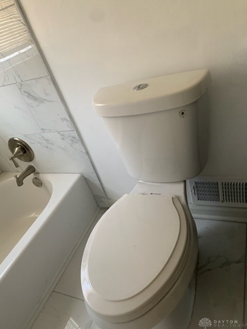 full bathroom featuring a washtub, marble finish floor, and toilet