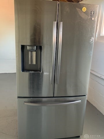 details featuring concrete block wall, finished concrete flooring, and stainless steel fridge with ice dispenser