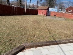 view of yard with an outbuilding, a fenced backyard, and a storage unit