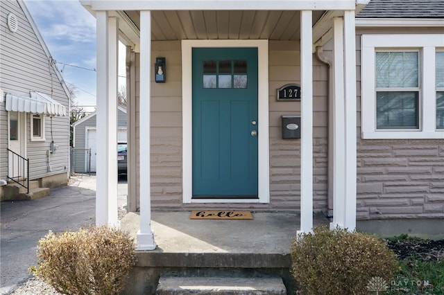 property entrance with a shingled roof and a porch