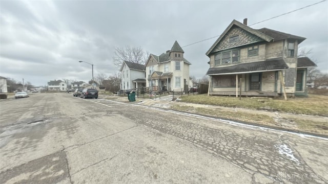 view of road featuring sidewalks, a residential view, curbs, and street lights