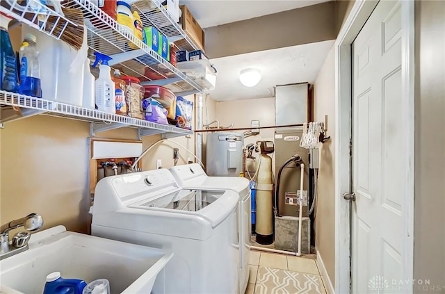 laundry area featuring laundry area, tile patterned floors, washing machine and dryer, water heater, and a sink