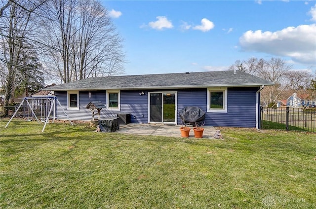 rear view of house featuring a shingled roof, fence, a lawn, and a patio