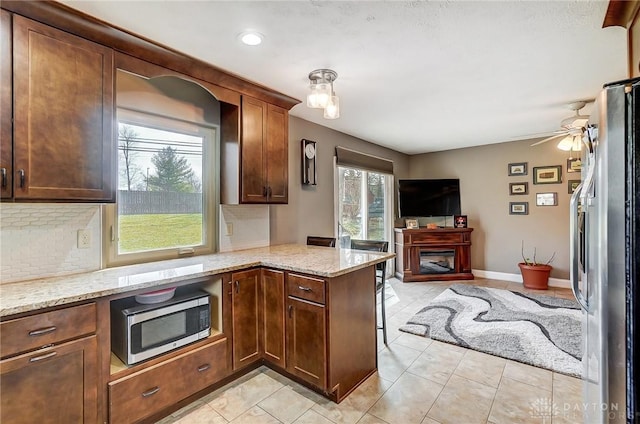 kitchen with appliances with stainless steel finishes, backsplash, and light stone countertops