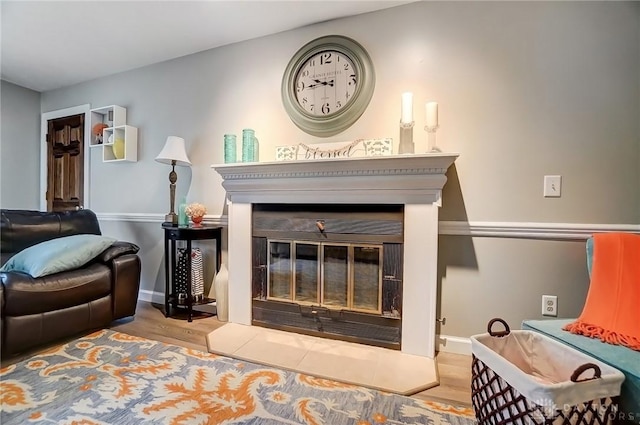 sitting room with a glass covered fireplace, wood finished floors, and baseboards