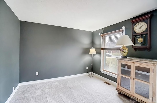 carpeted spare room with visible vents and baseboards