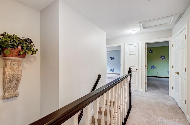 hallway with attic access, light colored carpet, and an upstairs landing