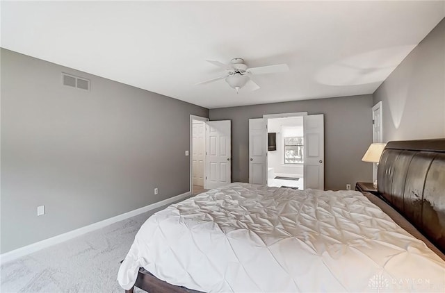 carpeted bedroom with connected bathroom, visible vents, ceiling fan, and baseboards