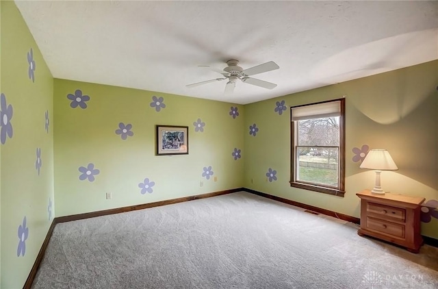 carpeted empty room with ceiling fan and baseboards