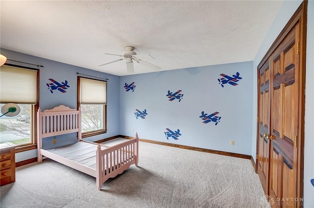 bedroom with a textured ceiling, carpet flooring, a ceiling fan, and baseboards