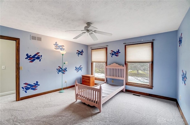 carpeted bedroom featuring visible vents, ceiling fan, a textured ceiling, and baseboards