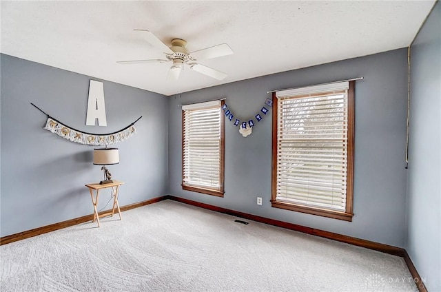 carpeted empty room with a wealth of natural light, visible vents, and baseboards