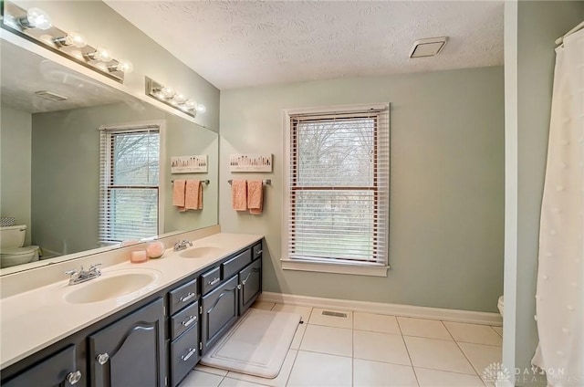 bathroom featuring toilet, a textured ceiling, visible vents, and a sink