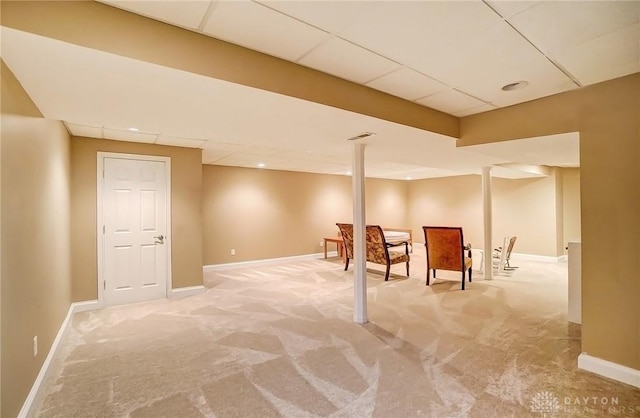 finished below grade area with light colored carpet, a paneled ceiling, visible vents, and baseboards