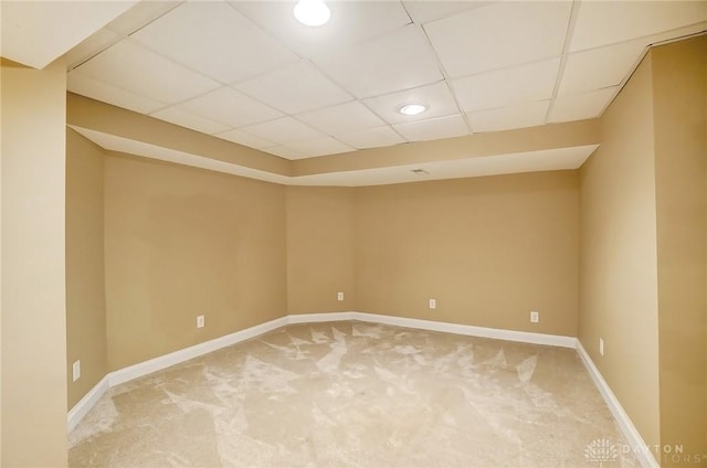 spare room featuring carpet floors, baseboards, and a drop ceiling