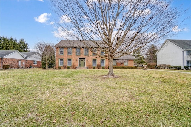 colonial home featuring brick siding and a front yard