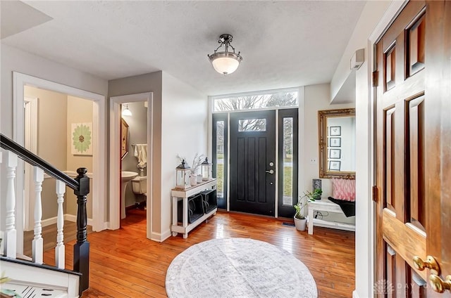 foyer entrance with stairs, baseboards, and hardwood / wood-style flooring