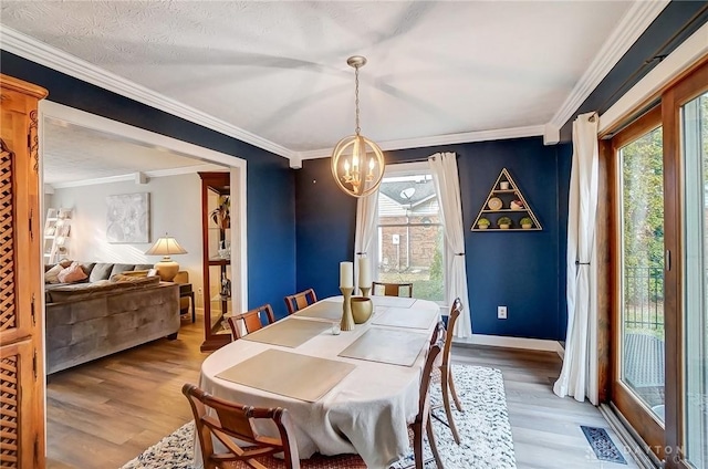 dining room with a chandelier, wood finished floors, visible vents, baseboards, and crown molding