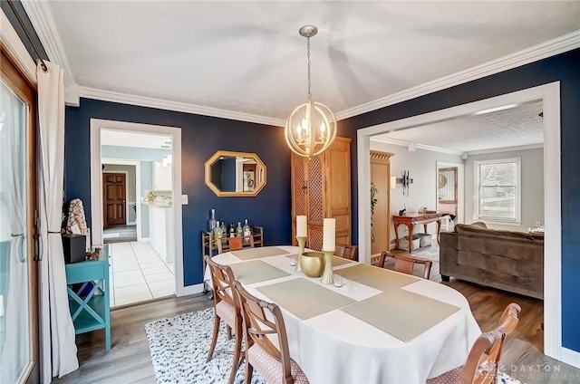 dining space with baseboards, an inviting chandelier, wood finished floors, and crown molding