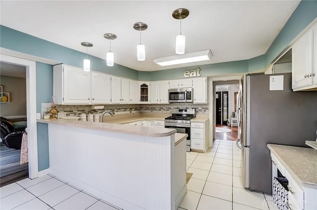 kitchen with stainless steel appliances, a peninsula, white cabinetry, light countertops, and decorative backsplash