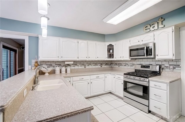 kitchen featuring appliances with stainless steel finishes, a sink, light countertops, white cabinetry, and backsplash