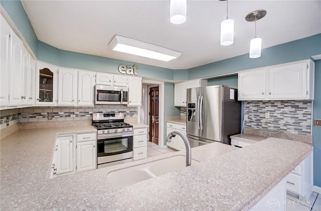 kitchen with stainless steel appliances, white cabinets, a sink, and decorative backsplash